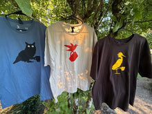 Load image into Gallery viewer, Three t-shirts with owl, hummingbird and egret designs hanging outdoors against a natural background
